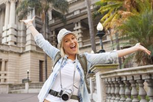 cheerful tourist arms up in front of historical building