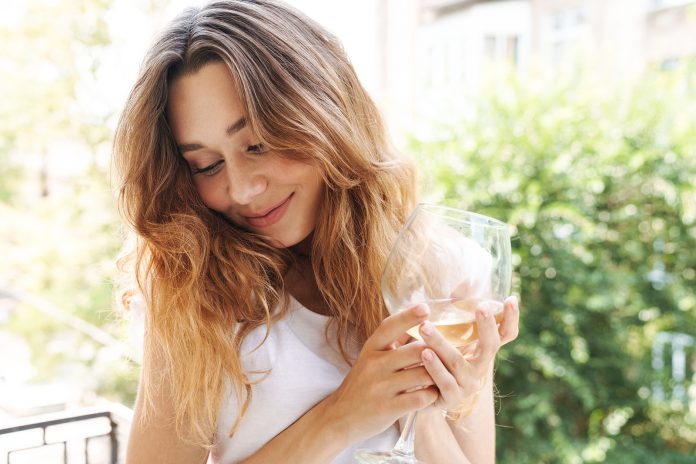 Image of beautiful young woman smiling and drinking wine outdoor