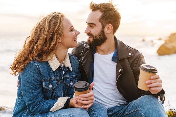 Image of beautiful young couple drinking coffee while walking by
