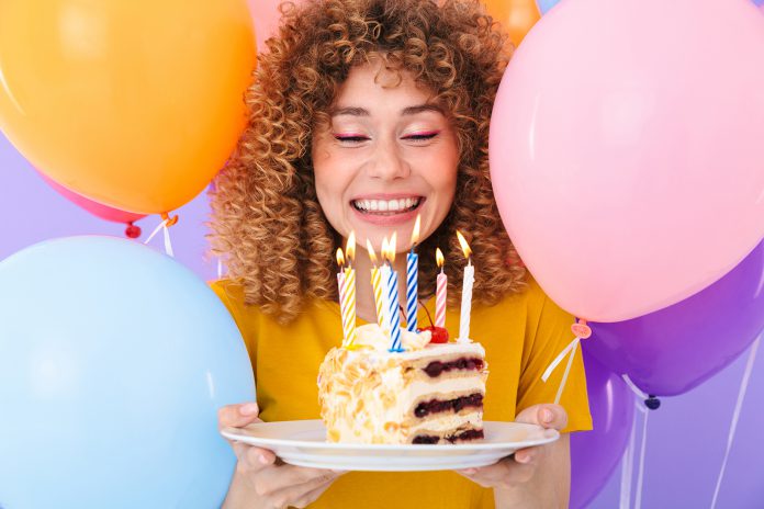 Image of delighted young woman celebrating birthday with multico