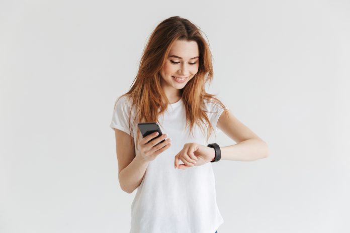Smiling woman in casual clothes holding smartphone