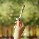 Young female painter holding painting brush at canvas