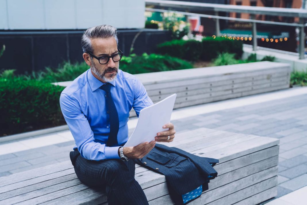 Concentrated,Middle,Aged,Man,In,Blue,Shirt,And,Glasses,Analyzing