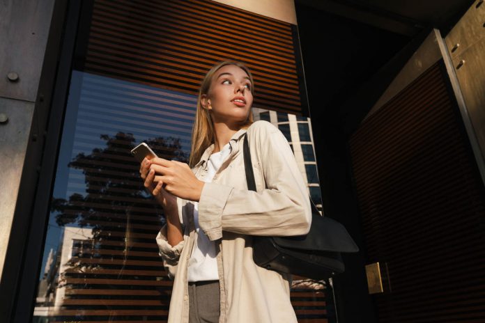 Nice,Serious,Blonde,Girl,Using,Mobile,Phone,While,Walking,At