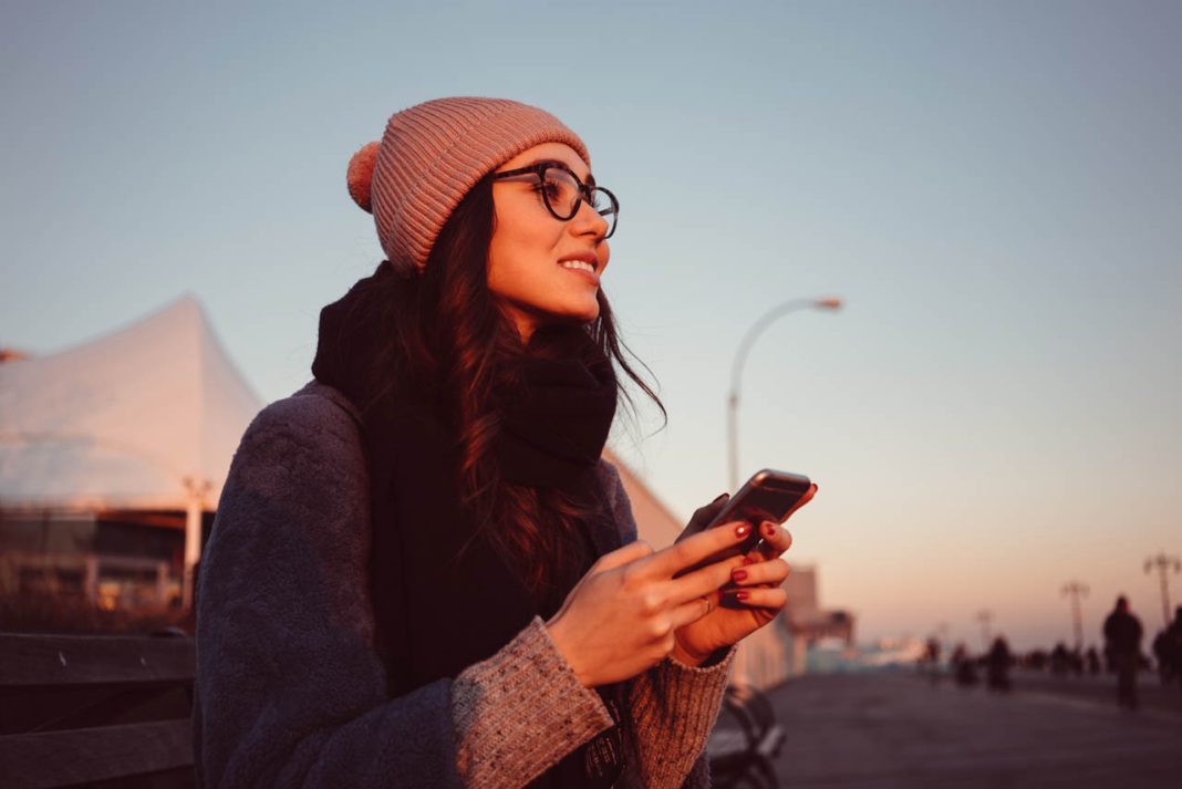 Portrait,Of,A,Lovely,Smiling,Girl,In,Eyeglasses,Holding,Mobile