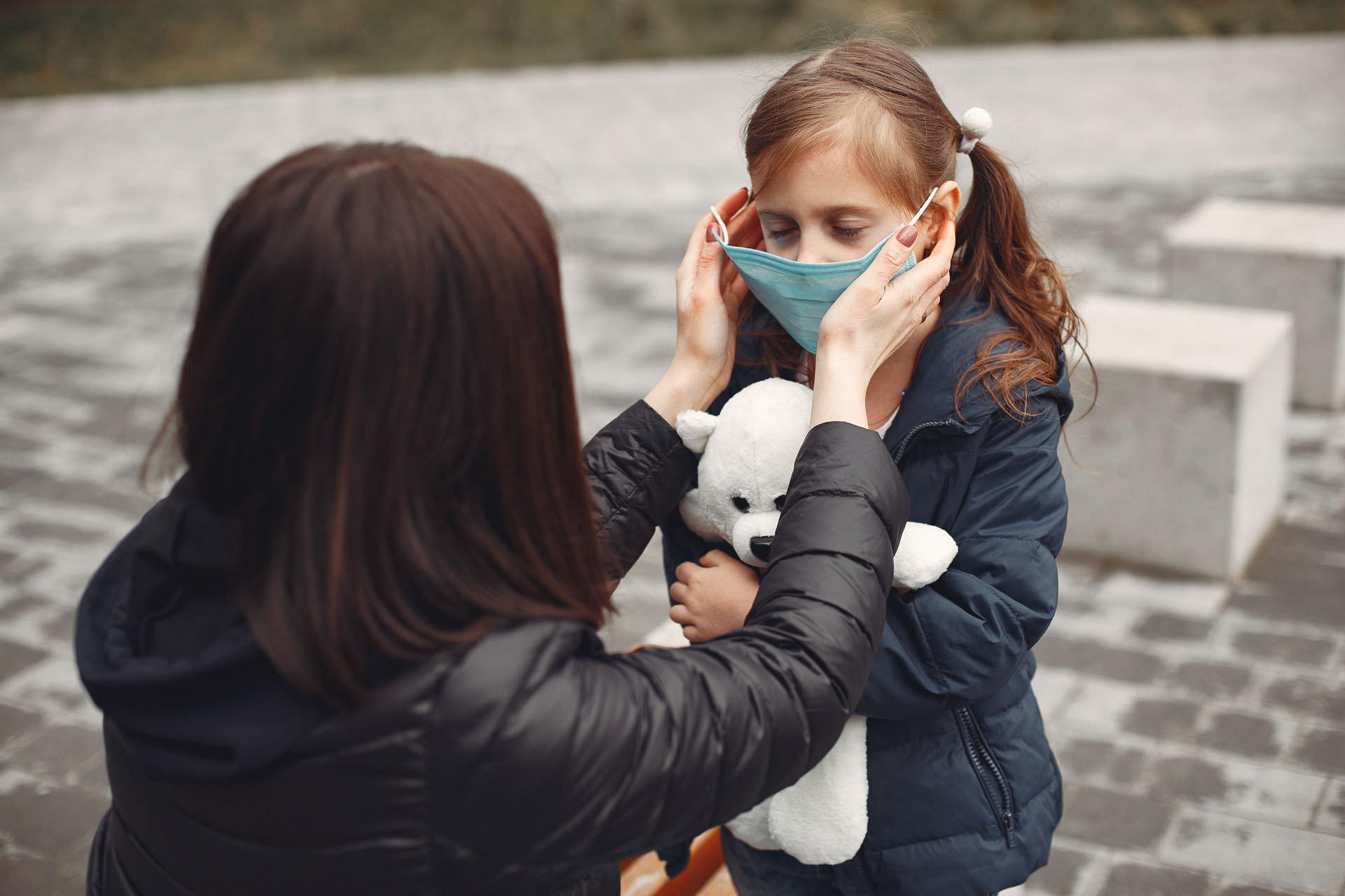 Woman in a disposable mask is teaching her child to wear a respirator