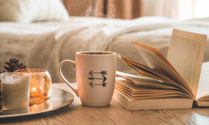 Book, cup of coffee and many candles on the home background.  Home and home decor. Candles flame