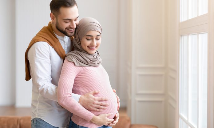 Muslim Couple Waiting For A Baby, Embracing Standing At Home