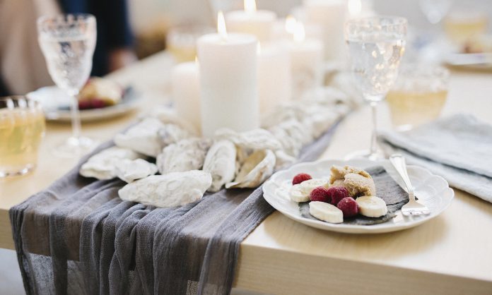 Lifestyle,USA,A table for a celebration meal with wine glasses filled and plates of fruit, and lit candles in the centre of the table.