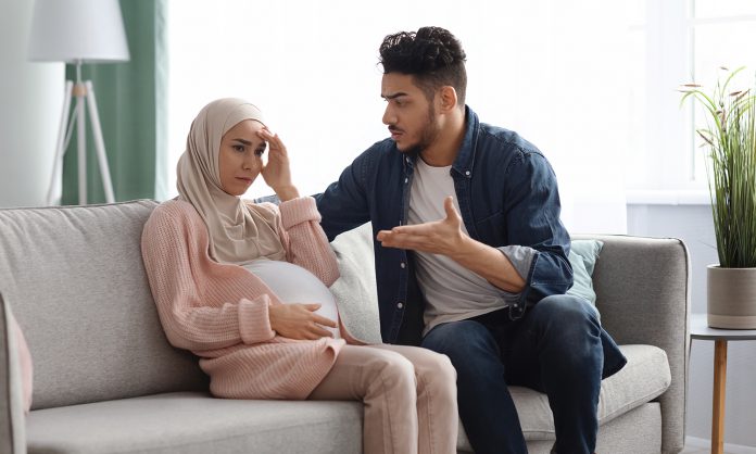 Agressive arab man arguing with his upset pregnant muslim wife at home